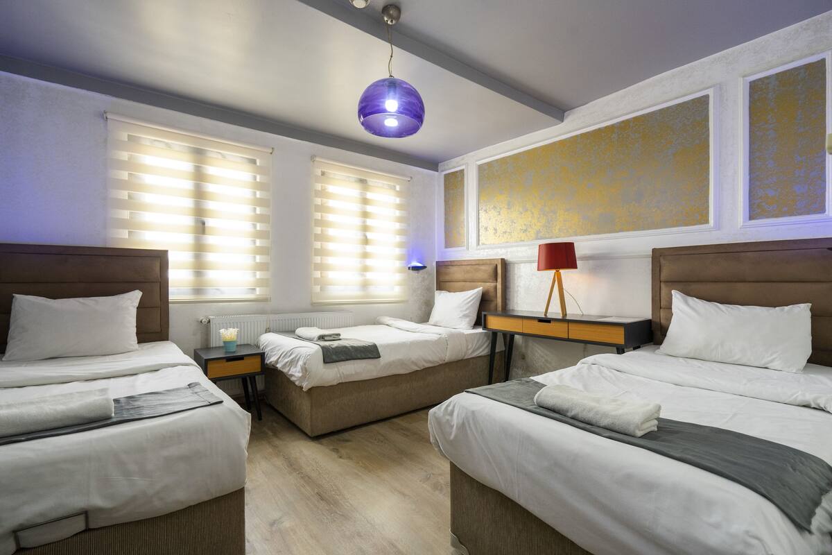 A hotel room with two beds, a nightstand, a lamp, and a ceiling light.