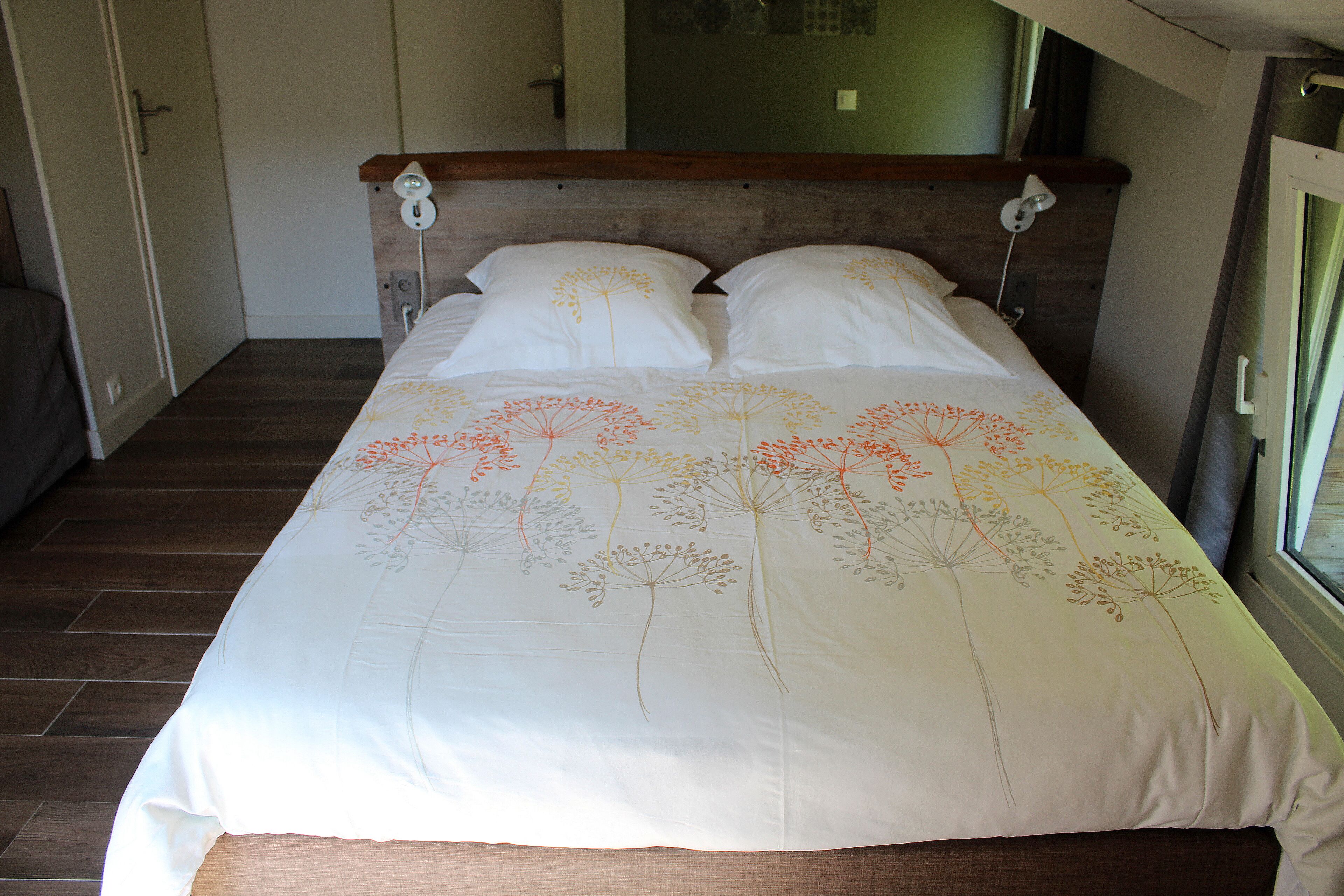 A bed with a floral bedspread, a wooden headboard, and bedside lamps.