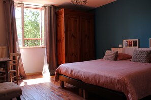 A bedroom with a bed, wooden wardrobe, a chair, and a window with curtains. - Moulin Pont Vieux - Chambres d'Hôtes (Mortagne-sur-Sevre)