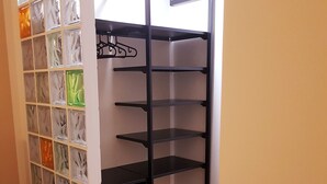 A corner room with a black metal shelving unit, a glass block wall, and a wooden floor. - Cairoli Rooms (Rome)