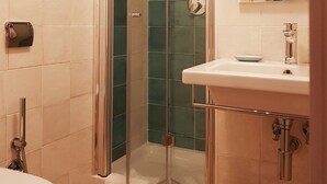 A bathroom with a glass-enclosed shower, a white sink with a bowl, and a toilet. - Cairoli Rooms (Rome)