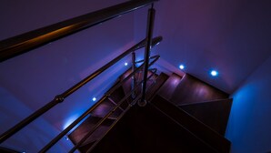 Un escalier avec des rampes en métal et des marches en bois, éclairé par un éclairage bleu.