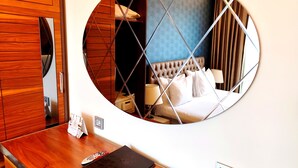 A hotel room with a wooden wardrobe, a round mirror reflecting the bed and nightstand, a remote control, and a black notebook on the table. - Old Port Hotel (Istanbul)