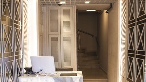 A hallway with a marble reception desk, a brown bench, and a staircase leading to a door with a geometric pattern. - Old Port Hotel (Istanbul)