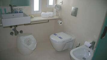 Een badkamer met een wastafel, toilet, bidet en een spiegel.