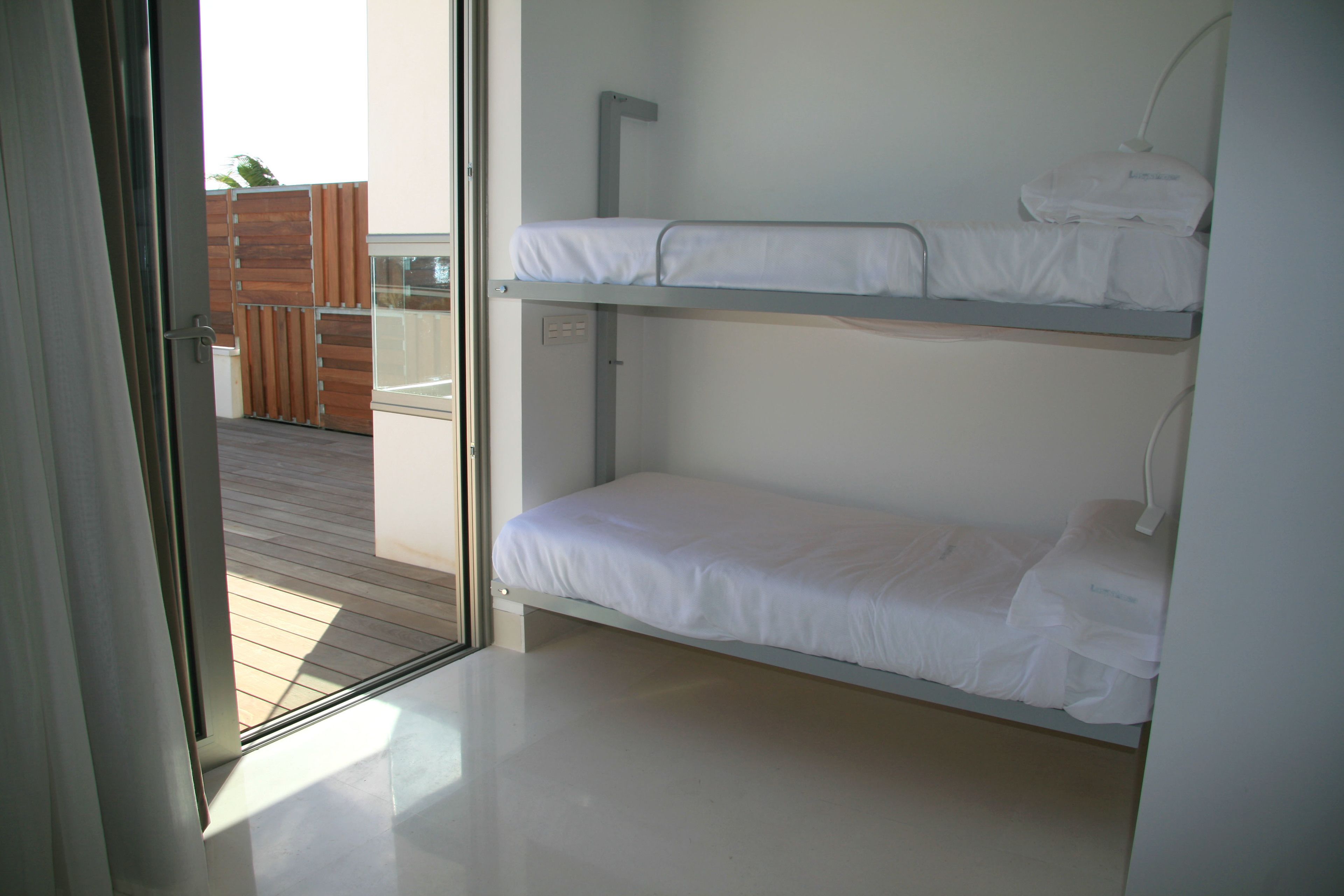 A bunk bed room with a wooden deck outside.
