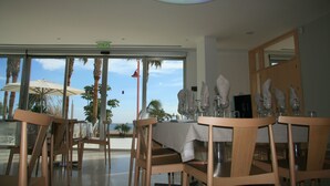 Un restaurante con vista al océano, con mesas y sillas de madera y una lámpara en el techo.