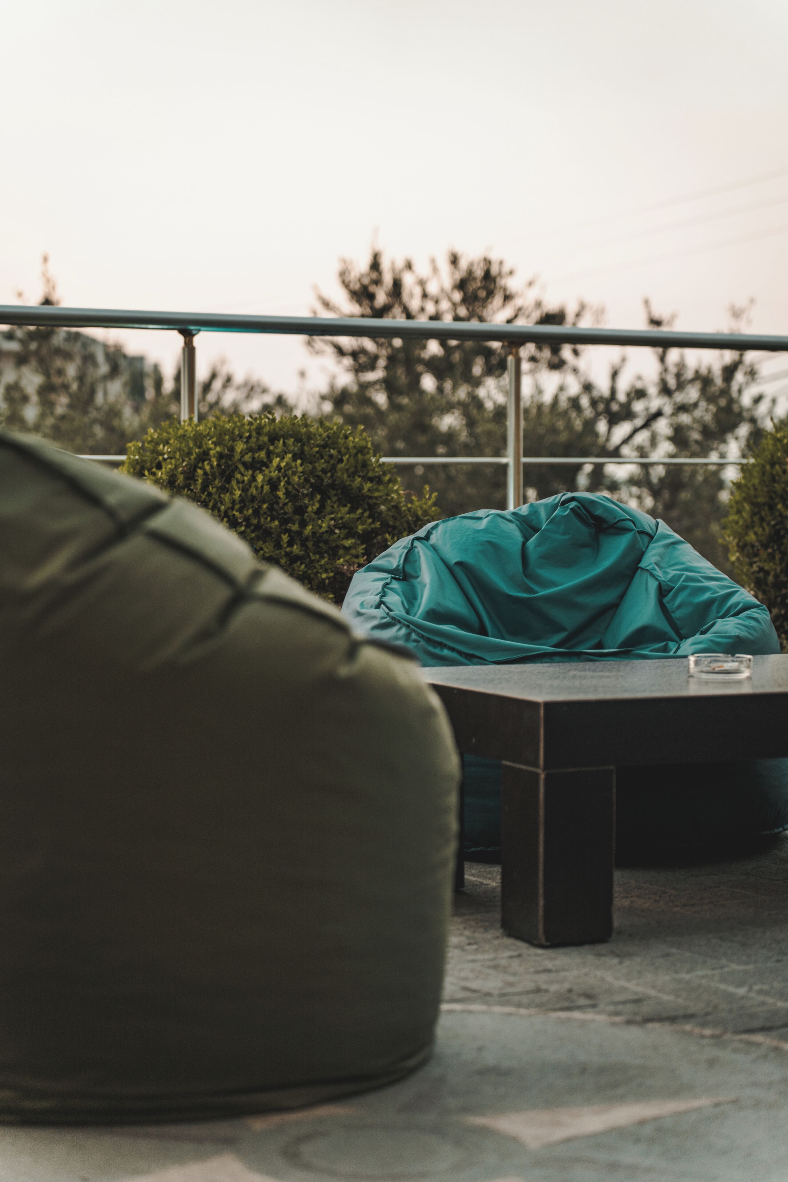 Un espace extérieur aménagé avec un fauteuil en forme de haricot vert, une table et un barbecue.