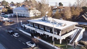 Un edificio moderno con un letrero que dice "Greve Steakhouse" en la planta baja, que presenta un techo plano y una escalera visible que conduce a los niveles superiores.