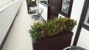 Un balcón con una fila de sillas y una jardinera con plantas.