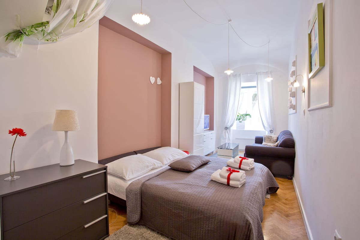 Ein modernes Schlafzimmer mit einem großen Bett, Nachttischen, einer Kommode und einer Sitzecke mit einem Sofa.