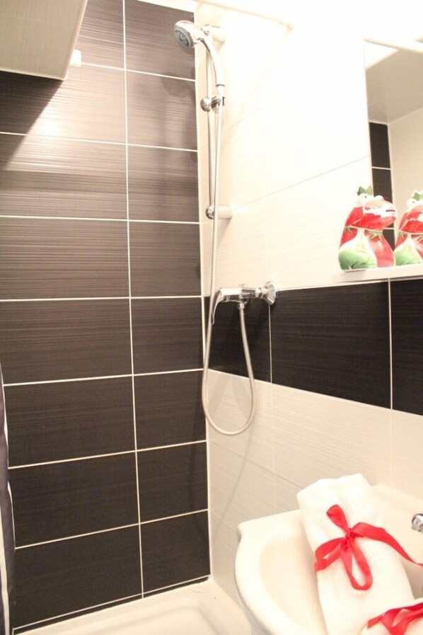 Un baño con ducha, lavabo y espejo.
