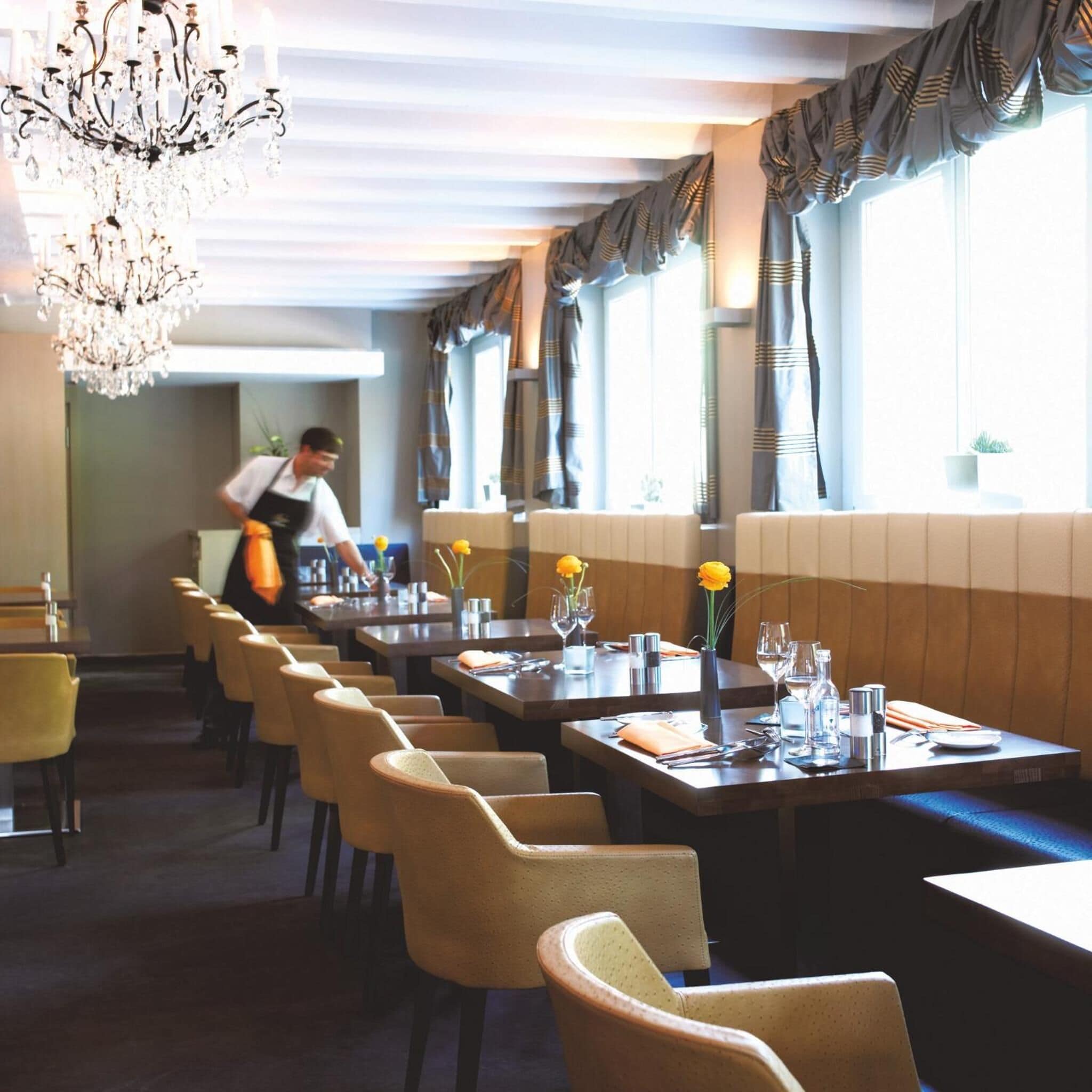 En restaurang med långa bord, stolar och en kristallkrona.