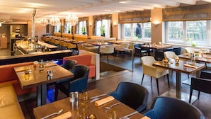 A modern restaurant with multiple dining areas, including a bar and booths.