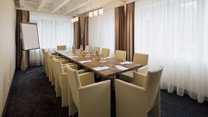 A conference room with a long table, chairs, a whiteboard, and curtains.