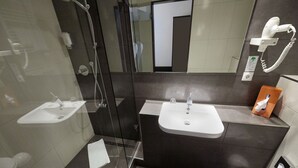 A modern bathroom with a glass shower enclosure, two sinks, and a toilet.