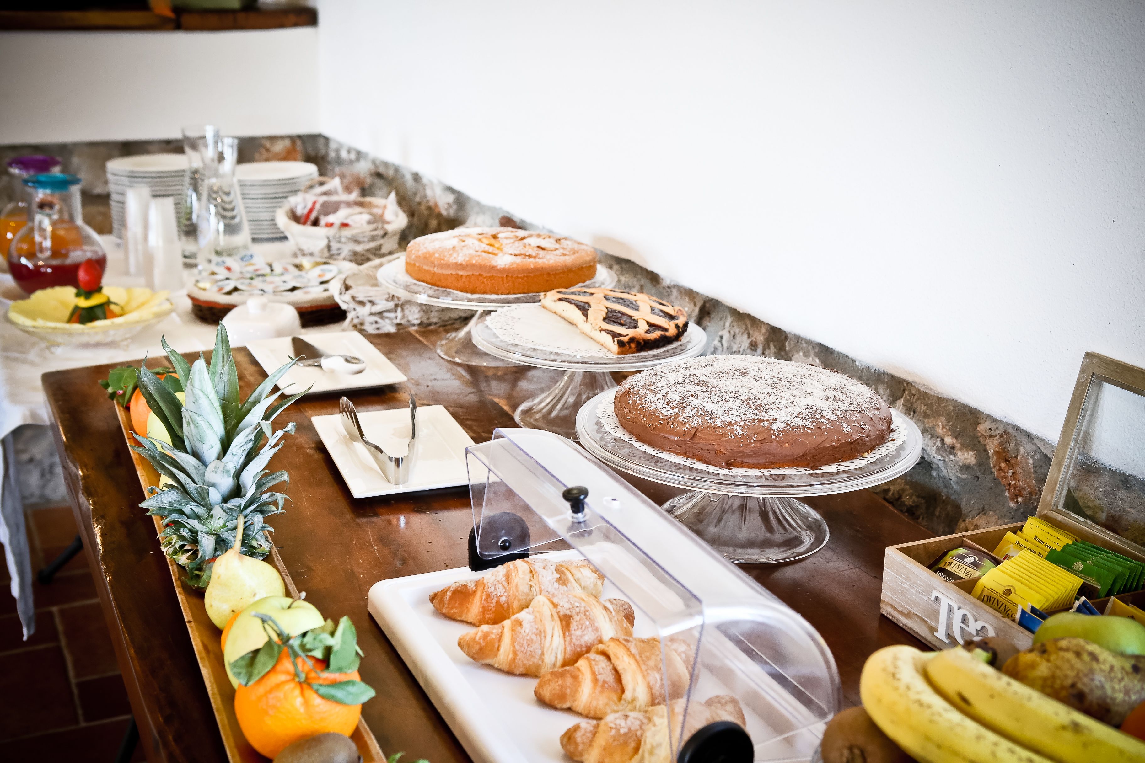 A buffet table with various food items including pastries, fruits, and a cake.