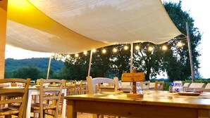 Un área de comedor al aire libre con mesas y sillas de madera, un toldo arriba y un cartel que indica una mesa reservada.