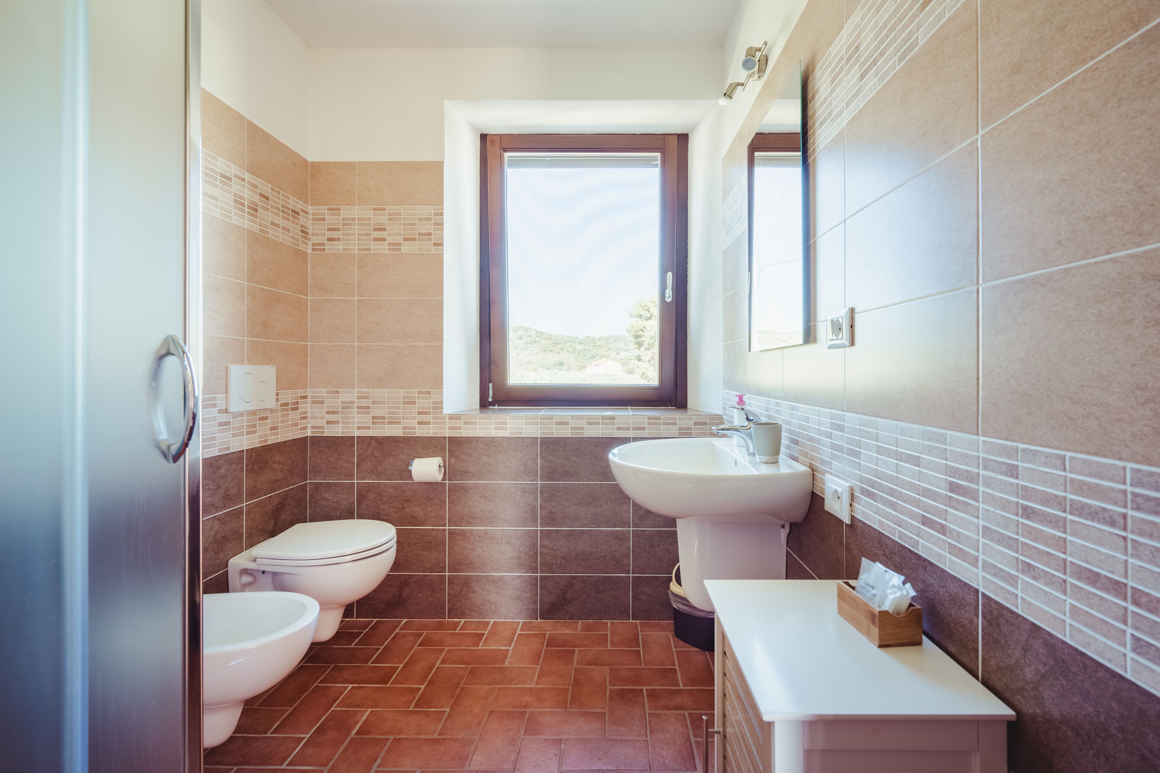 Un baño moderno con dos inodoros, un lavabo y una ventana.