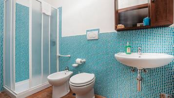 A bathroom with a shower, toilet, sink, and blue mosaic tiles.