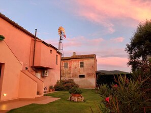 Un bâtiment à deux étages, doté d’un moulin à vent, d’un petit jardin et surplombant un ciel dégagé.