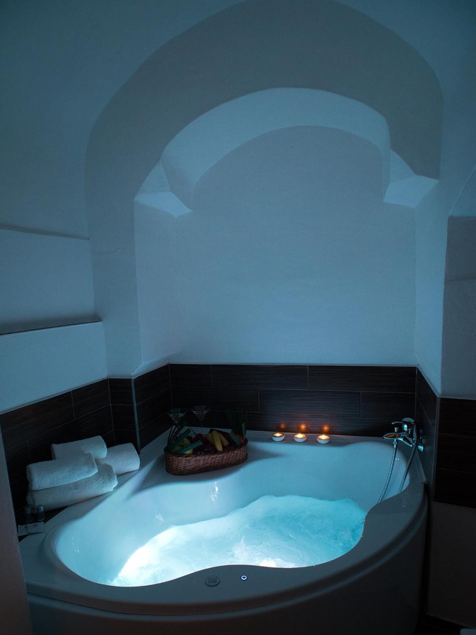 Een wellness badkamer met een vrijstaand bad, een mand met fruit en kaarsen.