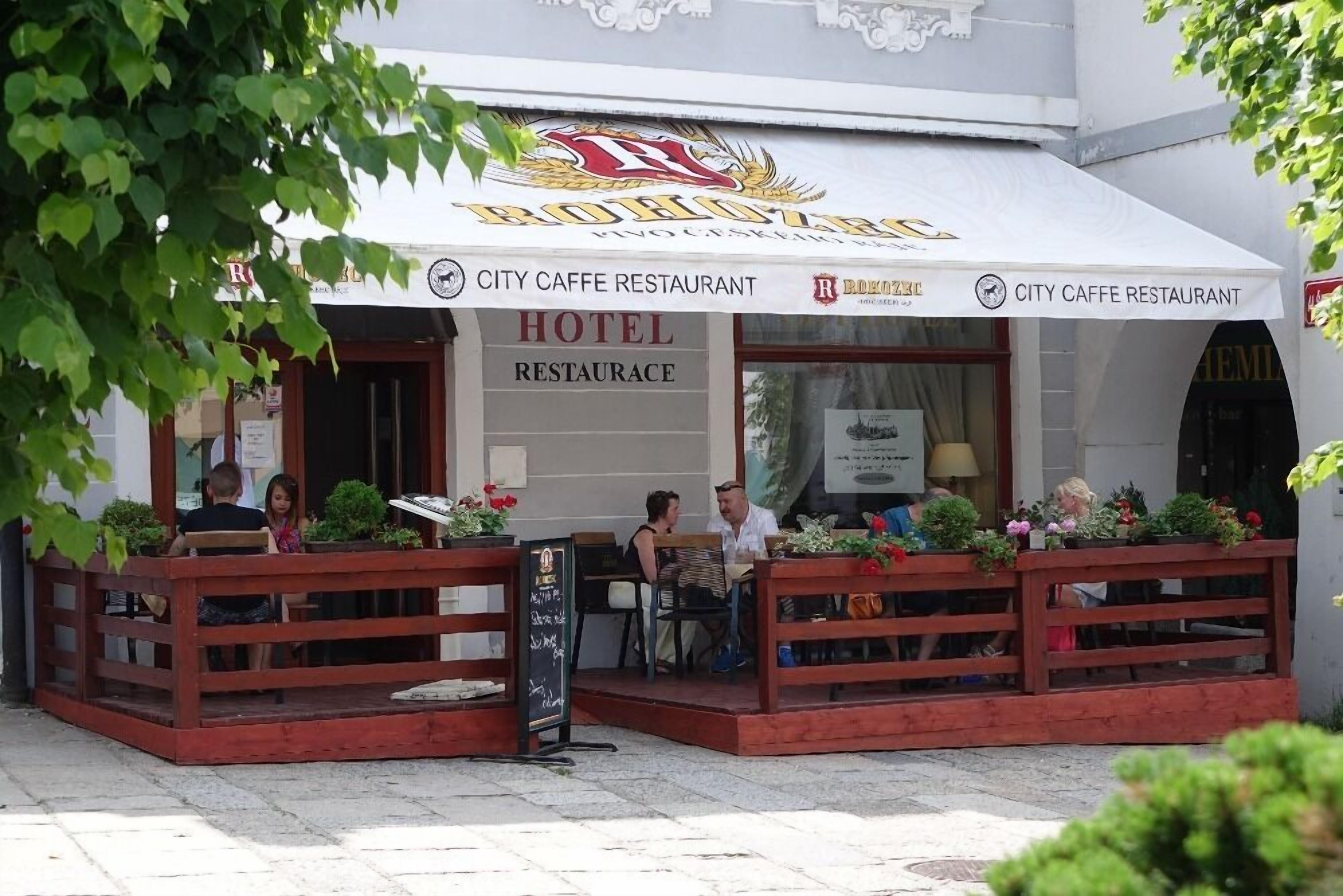 Ein Stadtcafé-Restaurant mit Außenbereich, einem Schild, das es als Hotelrestaurant kennzeichnet, und einer sichtbaren Speisekarte.
