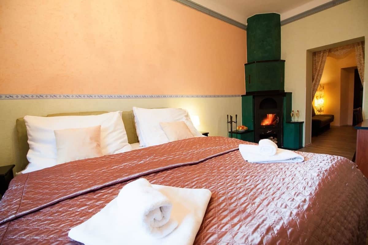 Ein Hotelzimmer mit einem großen Bett, einem grünen Kamin und Blick auf den Flur.