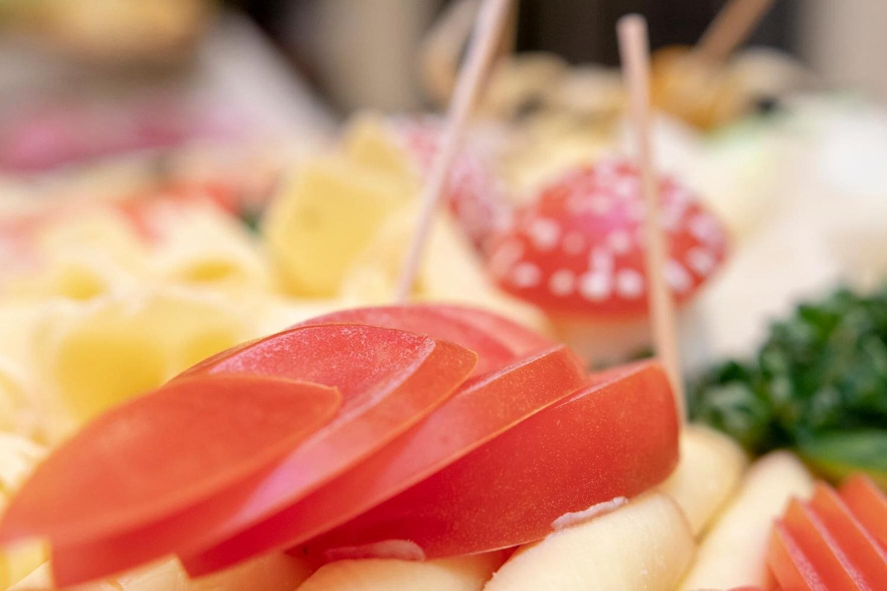 A close-up of a food display with various fruits and vegetables, including tomatoes and possibly other sliced items.
