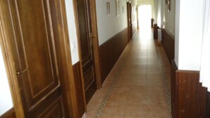 A long, narrow hallway with wooden doors on the left and a tiled floor. - As Maceiras (Puebla de Trives)