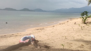 A beach with a sandcastle and a beach ball.