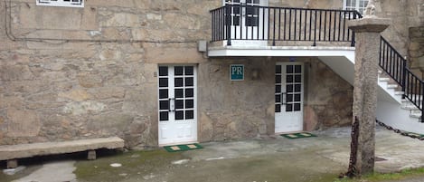 A stone building with a balcony, a staircase, and a sign indicating a parking area.