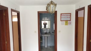 A hallway with a wooden door on the left, a blue-tiled wall, and a chandelier. - Pension Rural Areal (Padron)