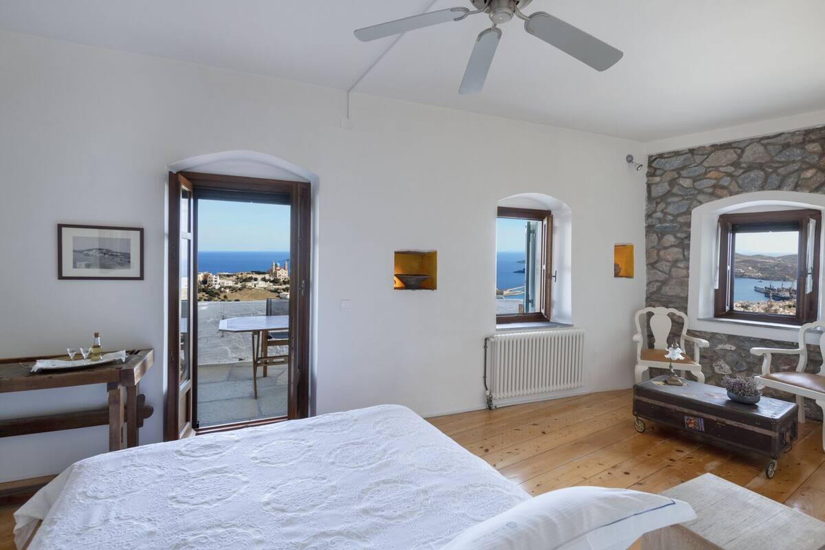 Un dormitorio con cama, escritorio y vista al mar.