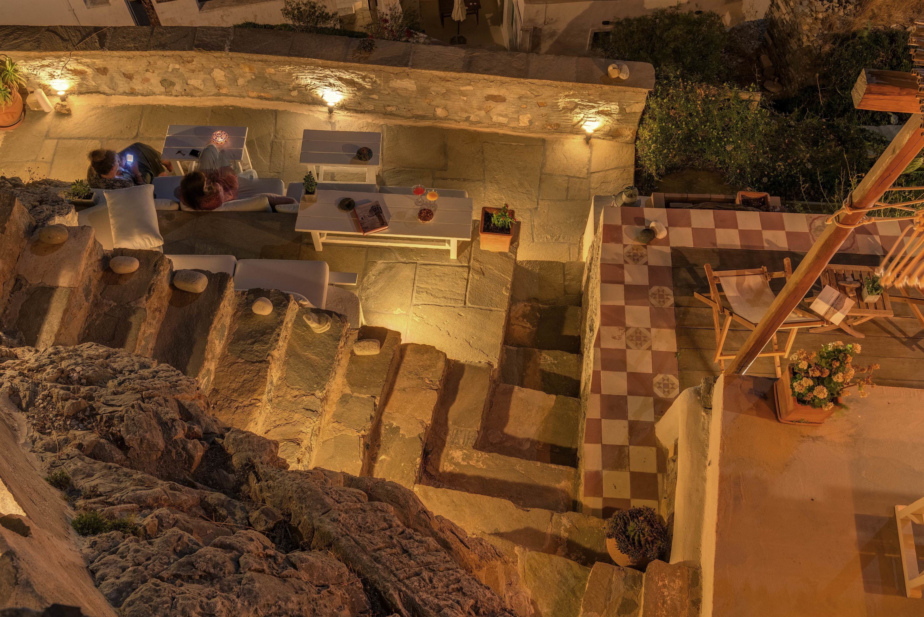 A stone-walled outdoor area with a checkered floor, stone steps, and a seating area with tables and chairs.