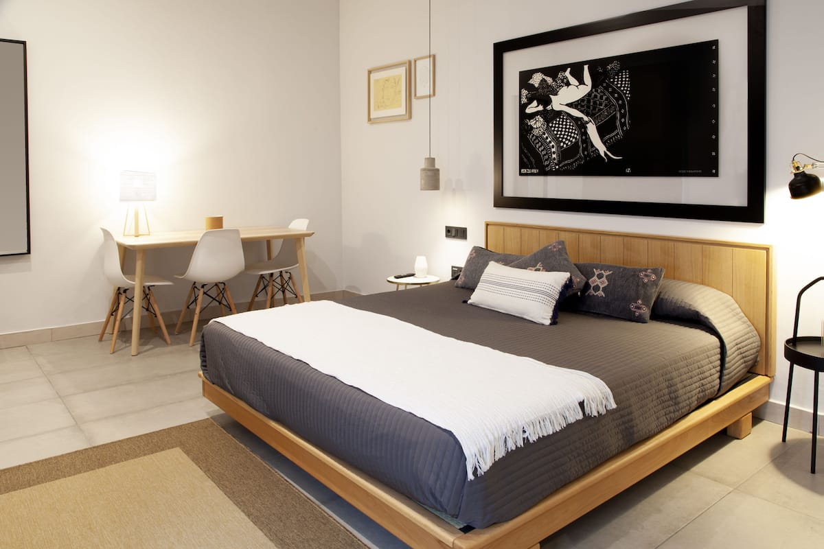 A modern bedroom with a large bed, bedside tables, a desk, and a chair.
