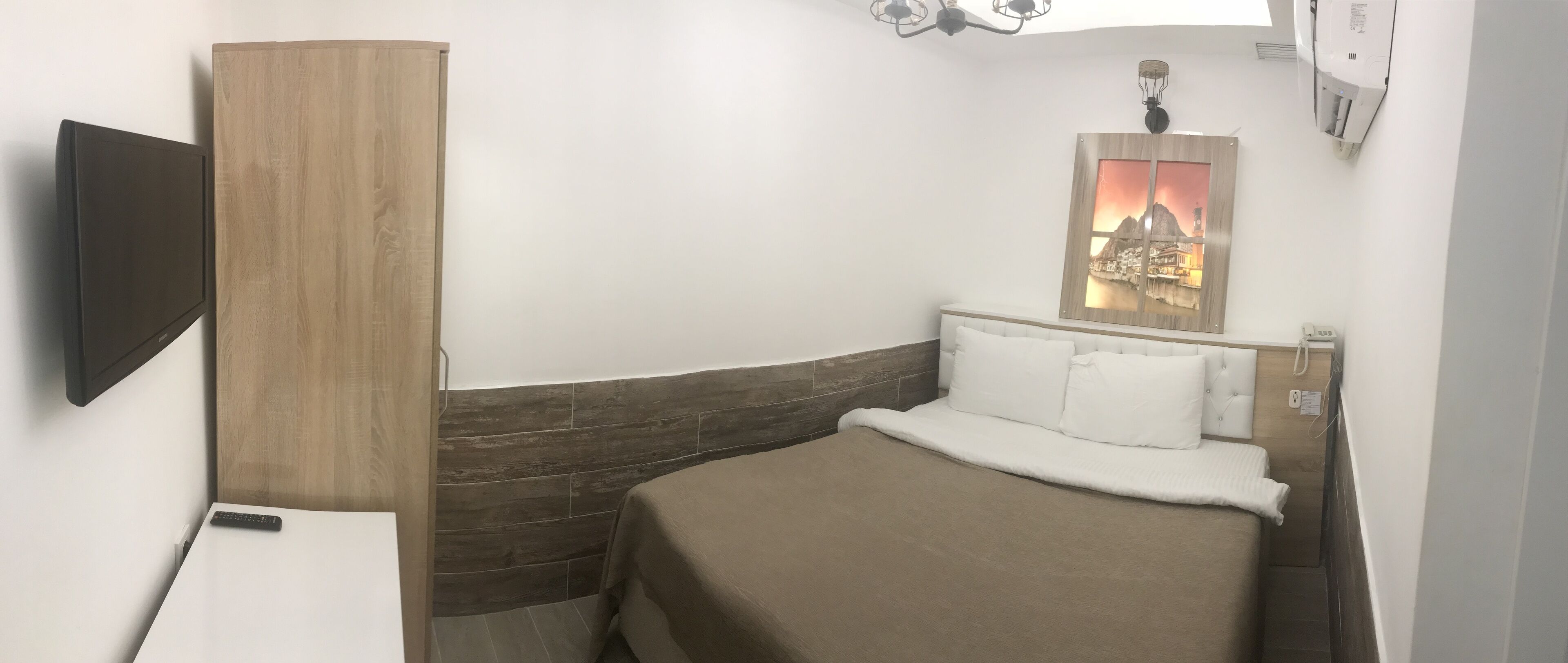 Une chambre d’hôtel comprenant un lit, un téléviseur fixé au mur, une armoire en bois et un élément décoratif mural.