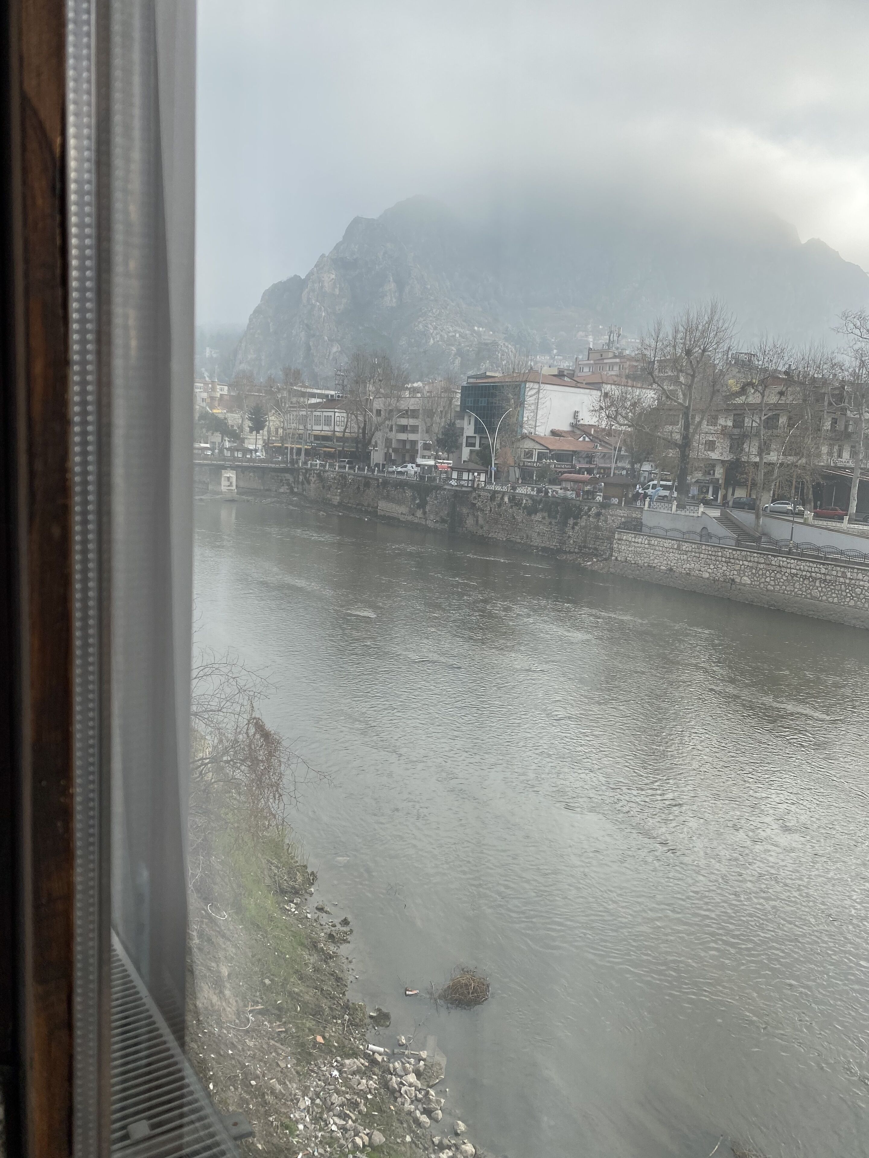 Un río con un muro de piedra a un lado y edificios al fondo.