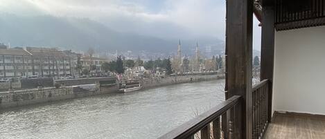 Un balcón con vista a un río, edificios y una torre distante.