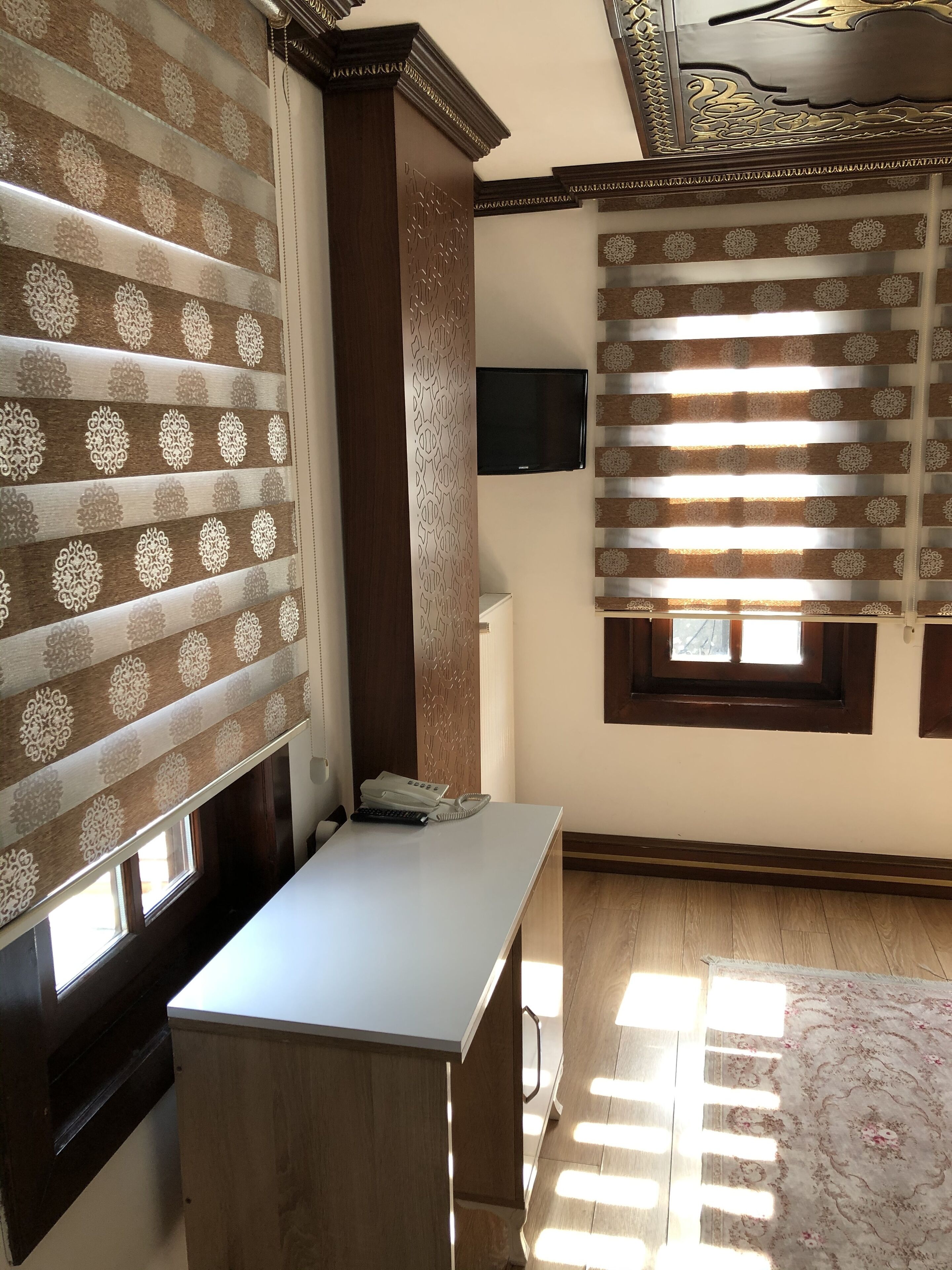 Una habitación con un escritorio de madera, un teléfono y un televisor fijado a la pared.