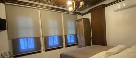 A bedroom with a large bed, a wooden nightstand, a desk, and a patterned rug.