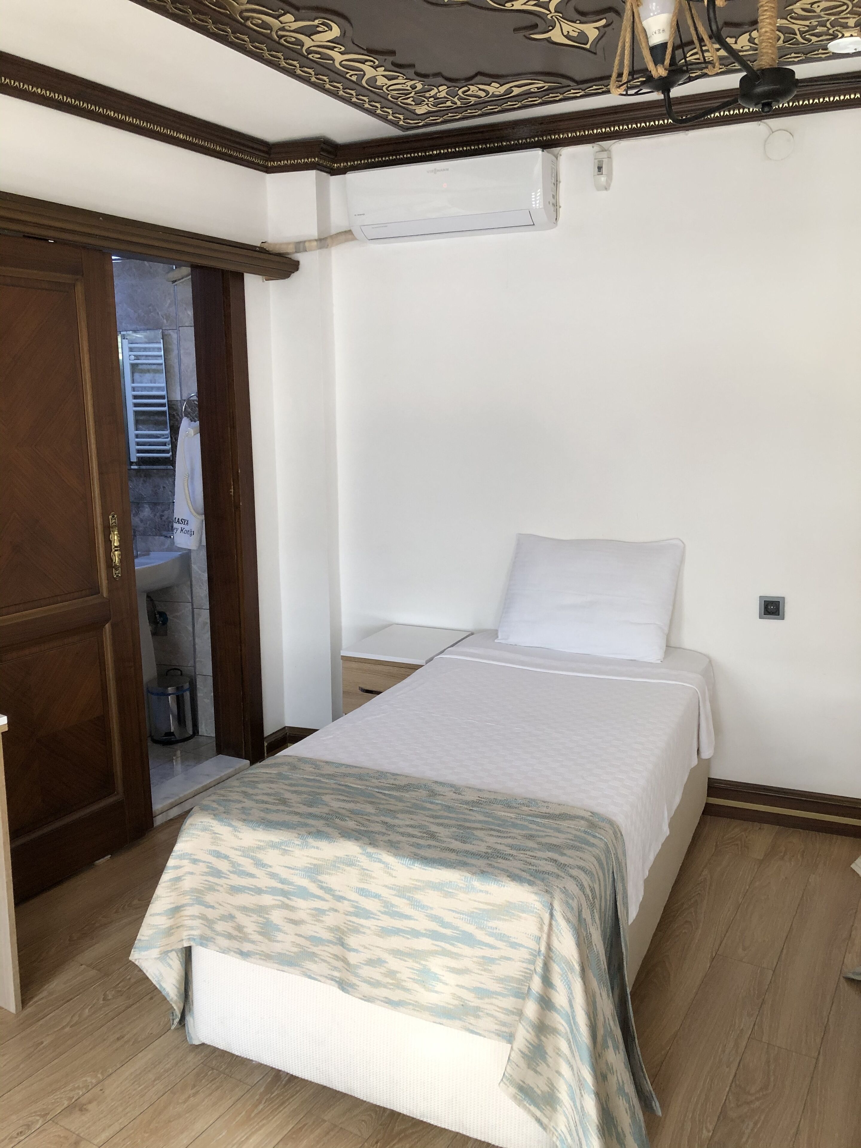 A bedroom with a bed, a wardrobe, and an air conditioning unit.