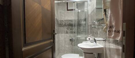 A bathroom with a toilet, sink, and shower area.