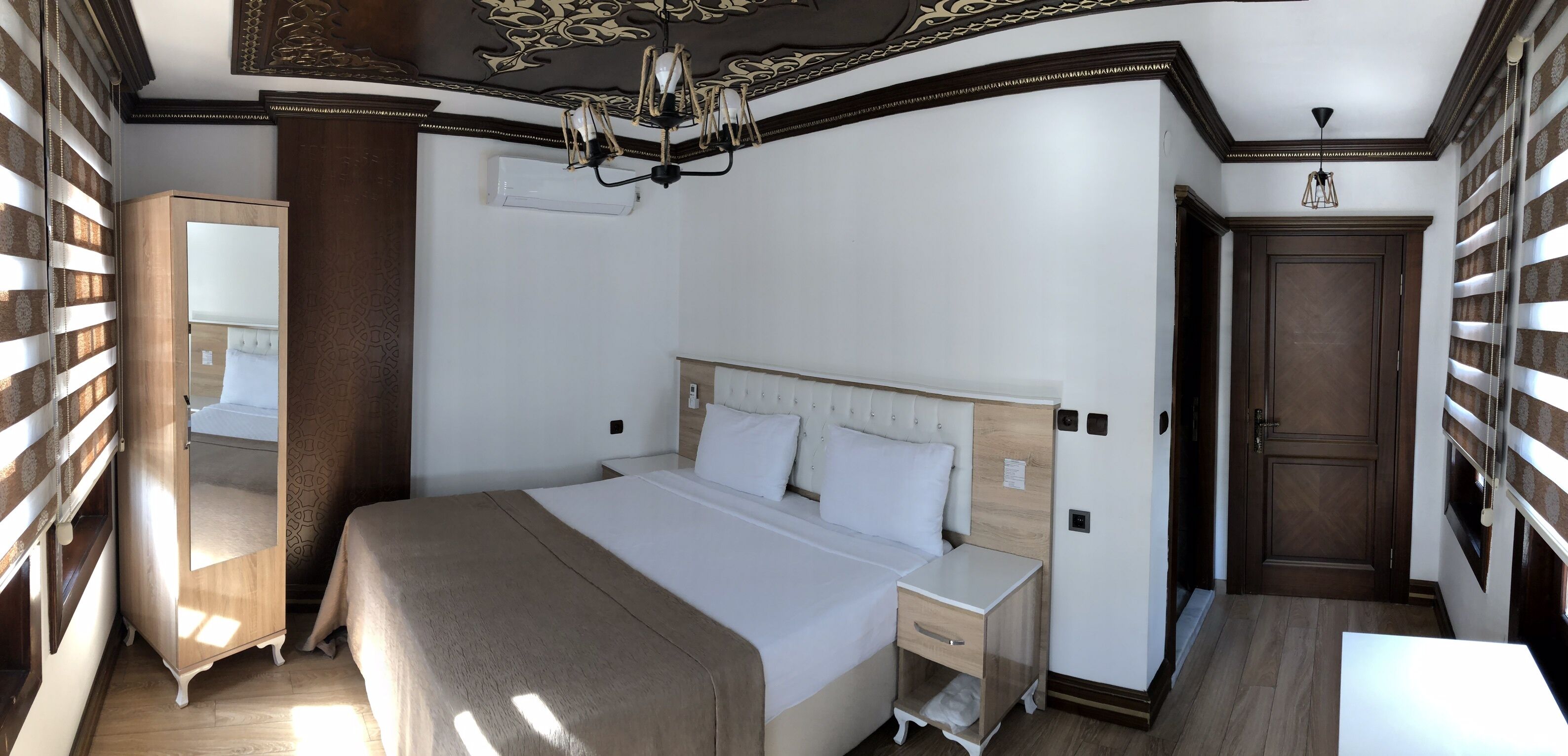 A bedroom with a large bed, a nightstand, a dresser, and a wardrobe.