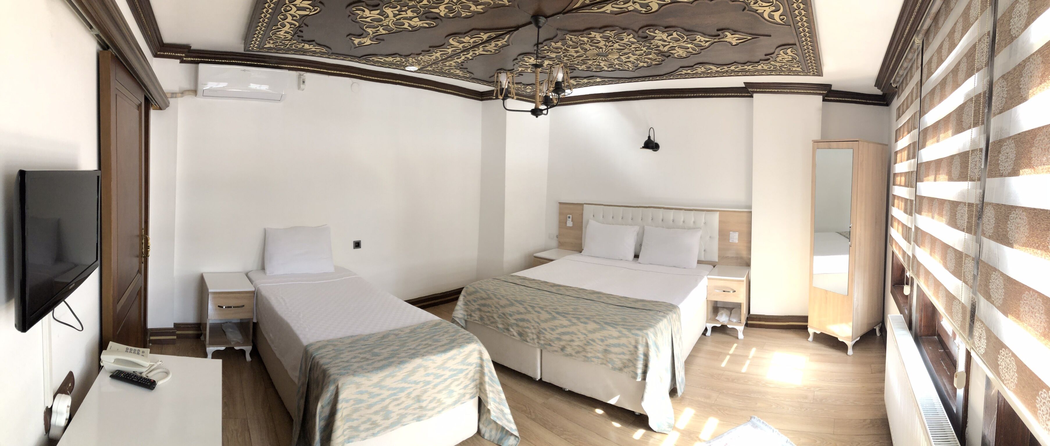 Une chambre d’hôtel avec deux lits, une télévision, une table de chevet et une armoire.