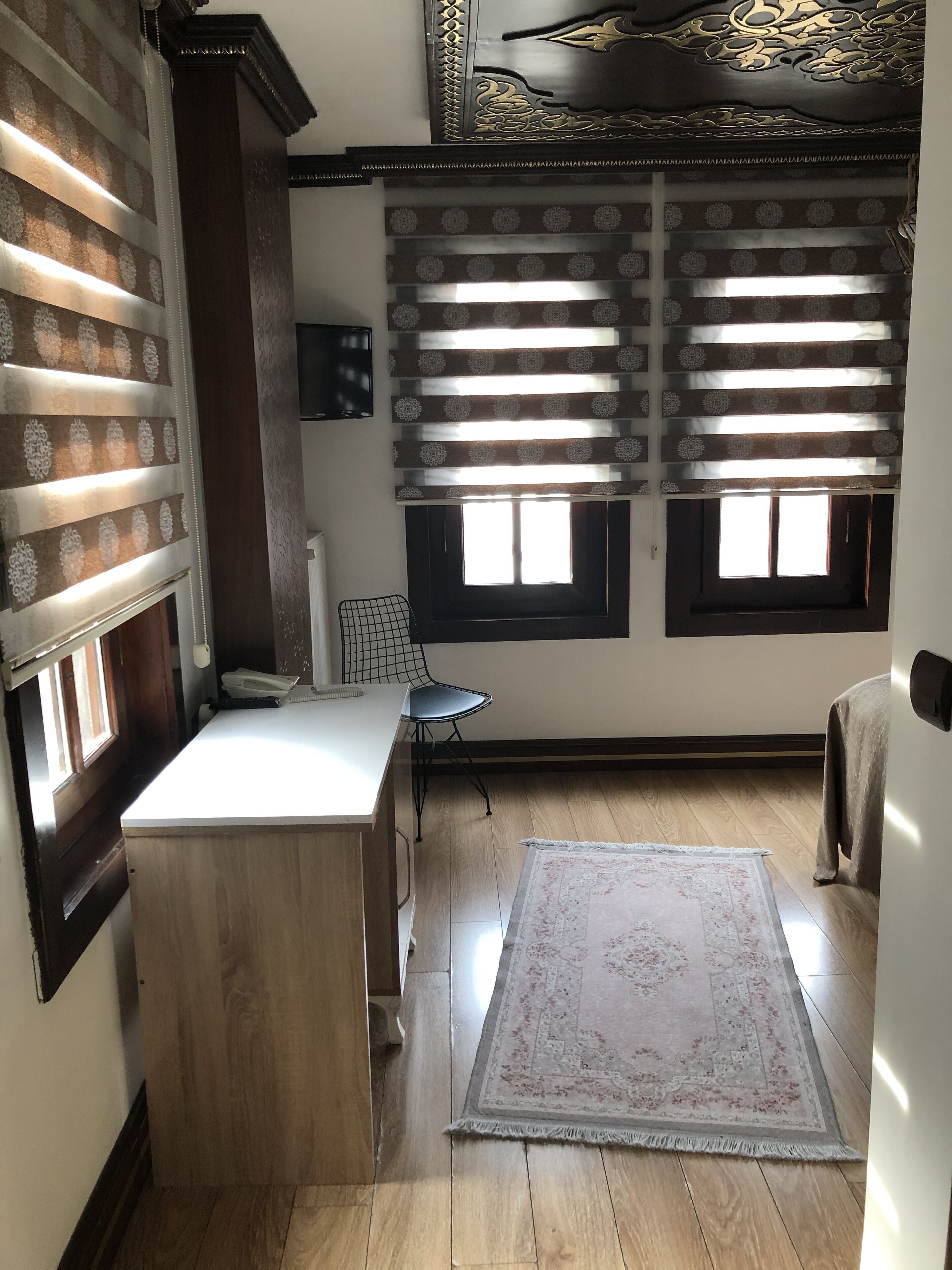 A compact kitchen with a wooden countertop, a small dining area with a chair, and a patterned rug on the floor.