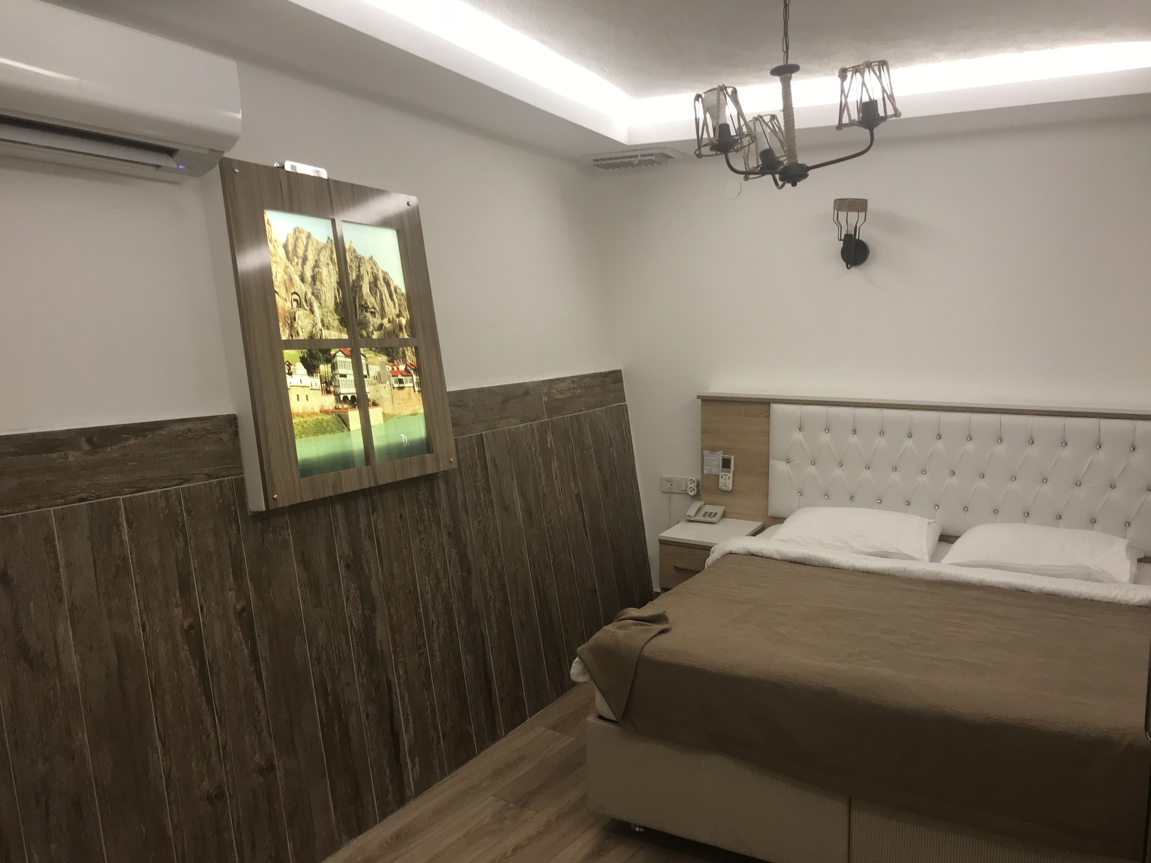 Un dormitorio con cama, mesita de noche y espejo adosado a la pared.