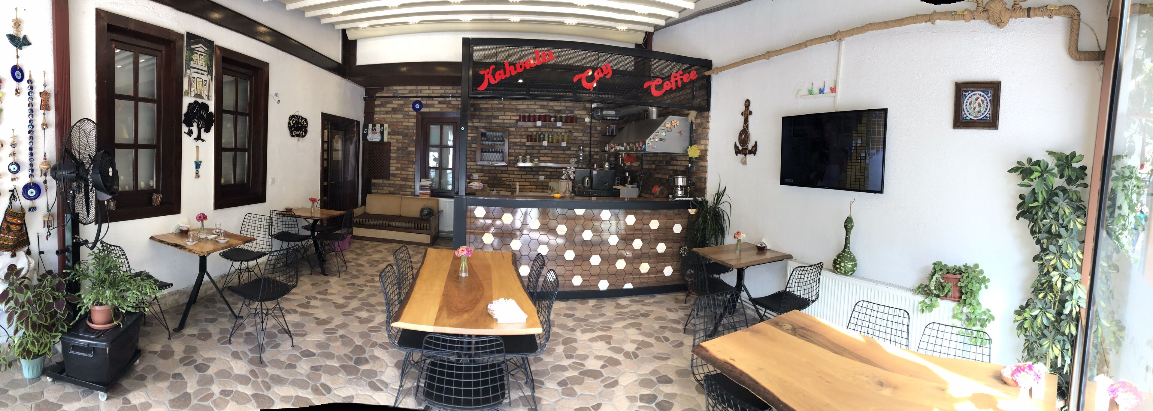 A cozy cafe with a wooden table and chairs, a coffee bar, and decorative wall elements.