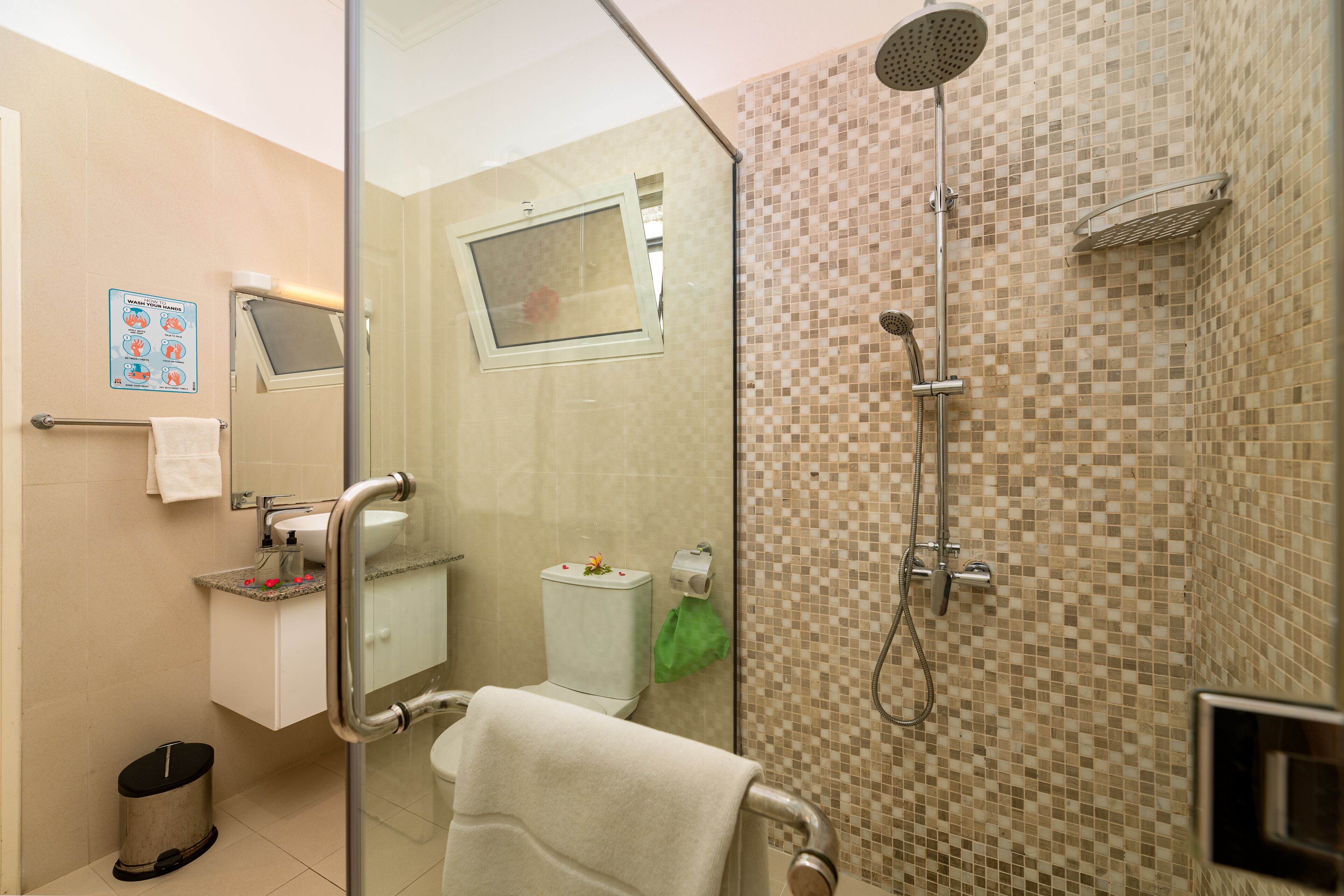 Un baño moderno con cabina de ducha de vidrio, un inodoro y un lavamanos.