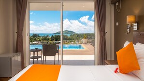 A hotel room with a bed, a view of a pool and mountains, and a table with chairs. - The Ridge Residence (Mahé Island)